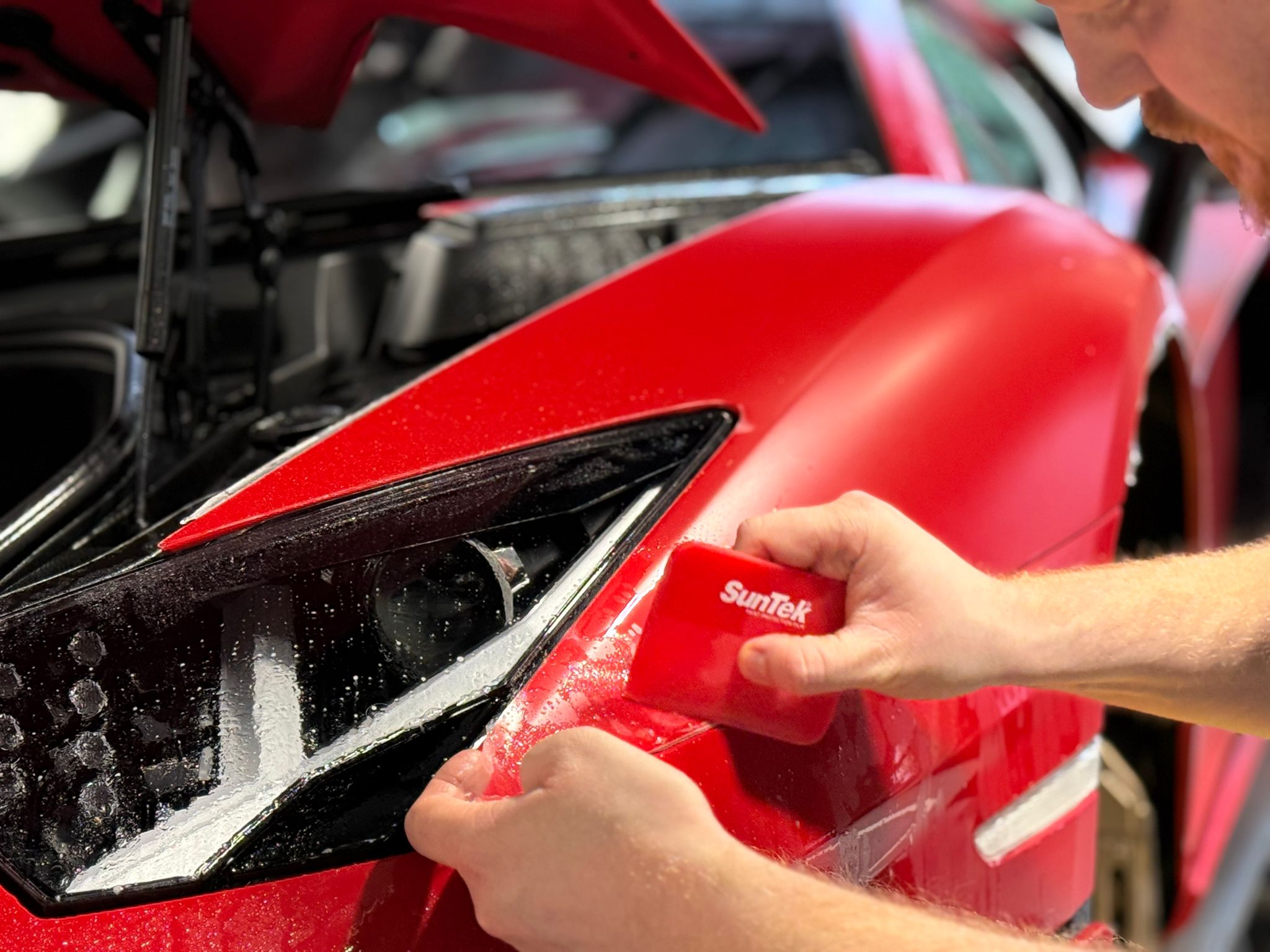 Professional applying protective film to luxury car